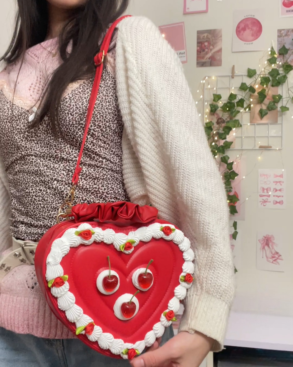 Person holding a red heart-shaped bag with a face design in a room.